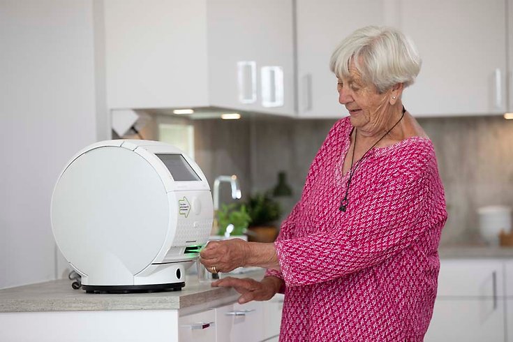 En äldre kvinna får sin medicin från en läkemedelsrobot.