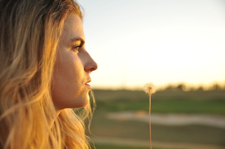 En ung kvinna tittar ut mot ett landskap och verkar fundera på framtiden.