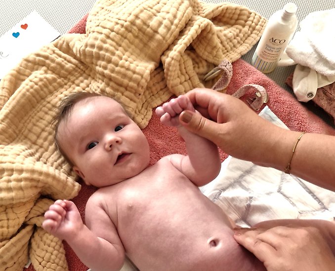 En bebis tittar rakt fram. Det ligger på en filt utan kläder.