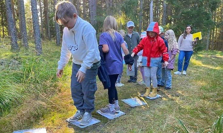 Barn balanserar på plattor i skogen.