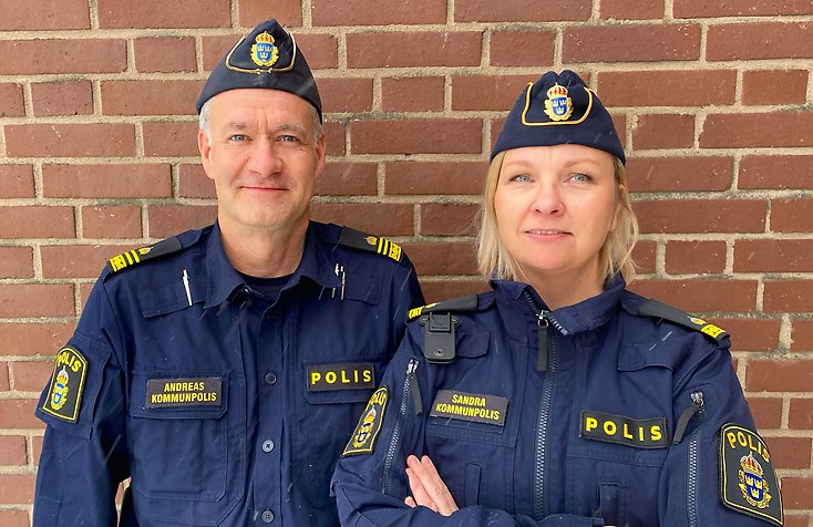 En manlig och en kvinnlig kommunpolis står framför polishuset i Värnamo.