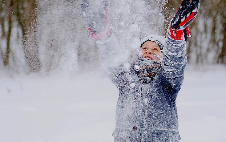 En pojke leker med snö.
