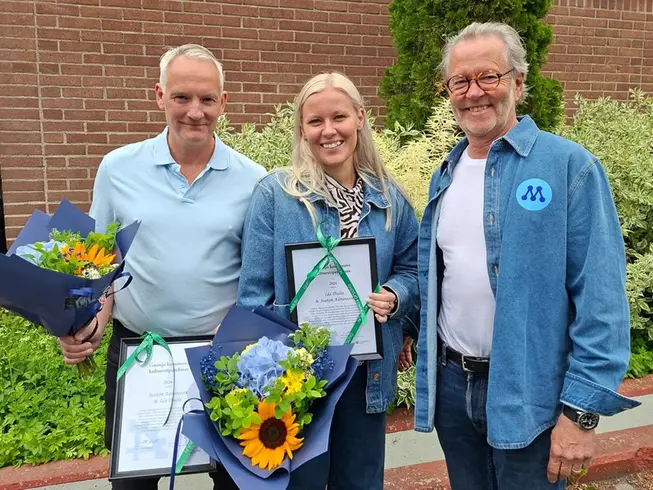 En man och en kvinna som håller i blomsterbuketter, och i varsitt inramad utmärkelse