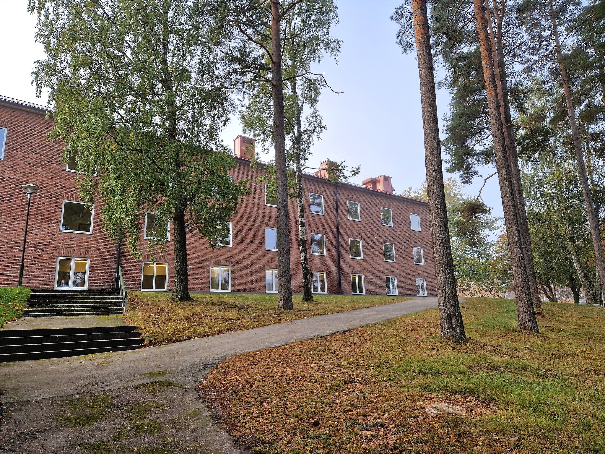 Bäckaskolan 7-9. Röd tegelbyggnad med träd utanför.