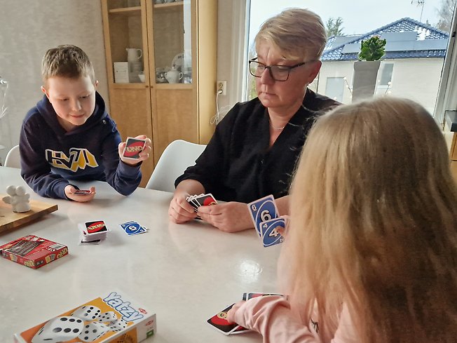 En kvinna och två barn spelar kortspel.