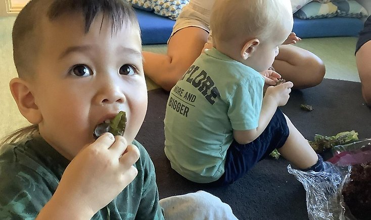 En pojke äter sallad.