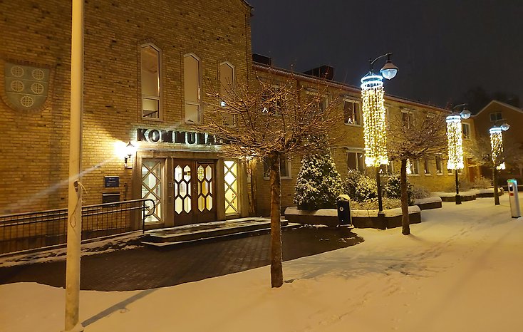 Kommunhuset i snö med julbelysning.