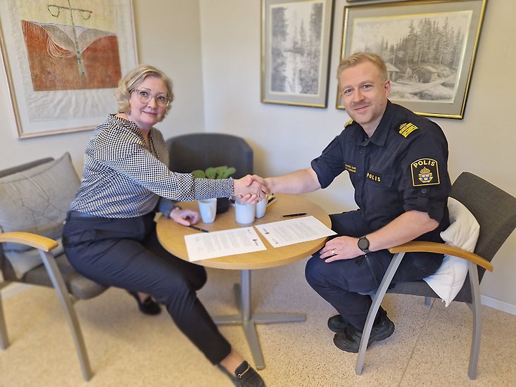Kristine Hästmark och Anders Sund sitter vid ett bord och skakar hand.
